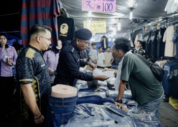 WAN MOHD. Zahari Wan Busu (tengah) mengedarkan borang balik kampung kepada peniaga ketika melakukan kempen pencegahan jenayah di Bazar Aidilfitri Madani Lestari dan Pintar 2025 di Dataran Sekilau di Kuantan Pahang. Turut serta Shafieq Johari (kiri).
