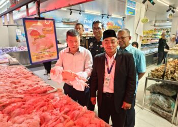 SIM Chon Siang (kiri) menunjukkan ayam yang dijual RM1 seekor di Pasar Raya BS Freshmart di Bandar Baru Jerantut di Jerantut, Pahang.