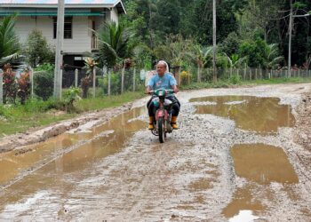 PENDUDUK terpaksa melalui jalan yang berlubang dan rosak di Kampung Bertam lama, Gua Musang, Kelantan. – UTUSAN/AIMUNI TUAN LAH