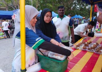 SEORANG petugas sukarela mengumpulkan lebihan makanan di setiap gerai peniaga Bazar Ramadan MITC, Ayer Keroh, Melaka. – UTUSAN/ MUHAMMAD SHAHIZAM TAZALI