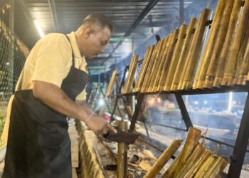 MOHD Kamal Abdullah sedang membakar lemang di tapak jualannya di Teluk Kumbar, Pulau Pinang.