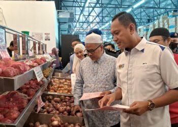 MOHD. Mufsi Lat (kanan) memeriksa barangan keperluan yang tersenarai dalam Skim Harga Maksimum Musim Perayaan di sebuah pasar raya di Dungun, Terengganu. -UTUSAN/NIK NUR IZZATUL HAZWANI NIK ADNAN