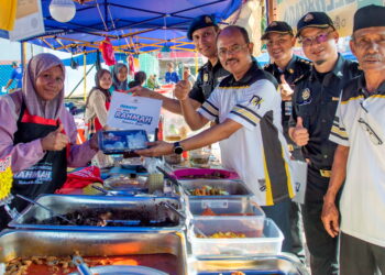 RAZALI Kassim (empat dari kanan) menunjukkan Menu Rahmah yang dijual seorang peniaga di Bazar Ramadan Muadzam Shah di Rompin, Pahang.