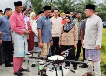 ANWAR Ibrahim (kanan) mendengar penerangan berkaitan projek perkhidmatan dron pertanian meracun di Kampung Tebuk Haji Dollah, Selinsing di Bagan Serai hari ini. - UTUSAN