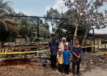 ZURAIDAH Muhammed bersama empat anaknya di hadapan rumah sewa mereka yang musnah dalam kebakaran di Kampung Lubuk Batu, Hulu Terengganu semalam.