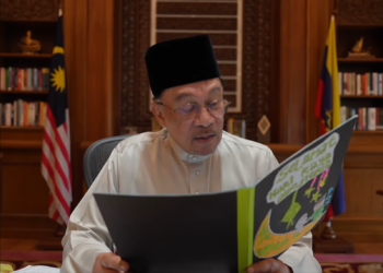ANWAR Ibrahim ketika membawa kad Hari Raya Aidilfitri yang ditulis oleh pelajar dan guru