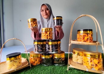NUR Solehah Fitri menunjukkan biskut raya harga rahmah yang dijualnya di Kampung Renek, Besut, Terengganu. – UTUSAN / WAN ZURATIKAH IFFAH WAN ZULKIFLI
