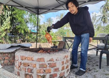 ARIFF Haiqal Zulkifli menunjukkan ayam yang dibakar di dalam ‘telaga’ yang diusahakannya di Kampung Kepala Gajah, Besut, Terengganu. - UTUSAN / WAN ZURATIKAH IFFAH WAN ZULKIFLI