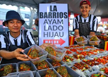 MUHAMMAD Luqman Nul Hakim Zahariman (kiri) menunjukkan beberapa menu berasaskan sambal lado yang dijualnya di Bazar Ramadan Stadium Tuanku Abdul Rahman, Paroi, Seremban. - UTUSAN/MOHD. SHAHJEHAN MAAMIN