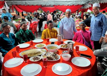RUSYDEE Abdullah berdiri (dua dari kanan) menyantuni penduduk Orang Asli yang menyertai majlis berbuka puasa sempena Program Ihya' Ramadan dan Program Santuni Kaum Gua Musang di Masjid Buluh, Gua Musang, Kelantan. - UTUSAN/AIMUNI TUAN LAH