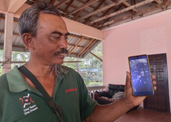 ZAHNUDIN Aluwi menunjukkan gambar ikan mati dalam kejadian pencemaran pada Februari lalu ketika ditemui di Pengkalan Nelayan Sungai Lereh, Klebang, Melaka. - UTUSAN/ MUHAMMAD SHAHIZAM TAZALI