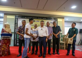 SAIFUDDIN Nasution Ismail menyerahkan sumbangan kepada salah seorang pemain KDA FC, Abdul Halim Saari pada Majlis Serahan Sumbangan Tabung Aidilfitri kepada pemain dan pegawai pasukan itu di Alor Setar, Kedah hari ini.-UTUSAN/SHAHIR NOORDIN.
