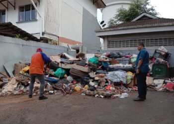MOHD. NORLISAM  Mohd. Nordin (kanan) melihat petugas SWM Environment membersihkan rumah sampah di Vila Rose, Taman Tampoi Indah, Johor Bahru.