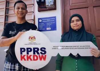 KASMAH Abdul Malik (kanan) dan Muhammad Khairul Amir Abdul Mutalib menunjukkan replika kunci PPRS ketika ditemui di kediaman mereka di Kampung Brisu, Alor Gajah, Melaka. - UTUSAN/MUHAMMAD SHAHIZAM TAZALI