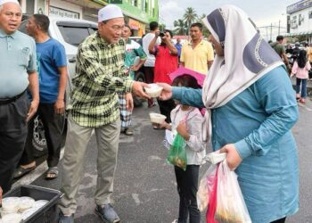 AWANG SOLAHUDDIN menyerahkan bubur lambuk kepada penduduk setempat di Bazar Ramadan Pekan Bandar Baru Tanah Merah, Pendang