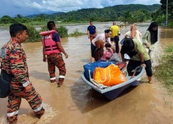 ANGGOTA Bomba membantu memindahkan mangsa terjejas banjir di Beaufort, semalam.