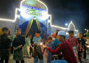 PENDUDUK Kampung Batu 10, Labu, Negeri Sembilan termasuk kanak-kanak bermain bunga api berlatarbelakangkan binaan gerbang yang dihasilkan para pemuda. – UTUSAN/MOHD. SHAHJEHAN MAAMIN