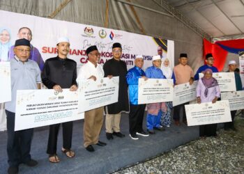 SAARANI Mohamad (tengah) bersama penerima cek tanggungjawab sosial masyarakat SKM di Tapah hari ini. - UTUSAN/MUHAMAD NAZREEN SYAH MUSTHAFA