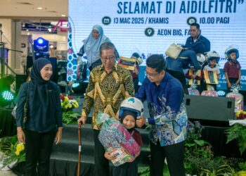 MOHAMMAD Nizar Jamaluddin (tengah) melihat murid dipasangkan topi keledar semasa program Pandu Berhati-hati dan Selamat di Aidilfitri di Ipoh, Perak hari ini. - UTUSAN