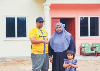 JULIZA Che Hamzah bersama suami dan anak bongsu di hadapan kediaman baharu mereka di Felda Sungai Koyan 3 di Lipis, Pahang. 
– UTUSAN/NORFARHIZA MOHD. ATAR