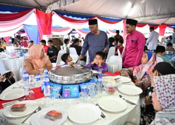 AHMAD Said (berdiri, dua dari kanan) menyampaikan sumbangan duit raya kepada seorang penerima pada Program Ikatan Kasih Madani di Bandar Al Muktafi Billah Shah, Dungun, Terengganu. - UTUSAN/NIK NUR IZZATUL HAZWANI NIK ADNAN