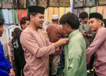 FAKHRURAZI Musa membantu pelanggan memakai baju Melayu yang dijual di TTC, Kuala Terengganu. - UTUSAN/PUQTRA HAIRRY ROSLI
