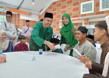 MOHD. Jafni Md. Shukor menyampaikan duit raya kepada kanak-kanak yang hadiri di Majlis Rumah Terbuka ADUN Bukit Permai, Kulai.
