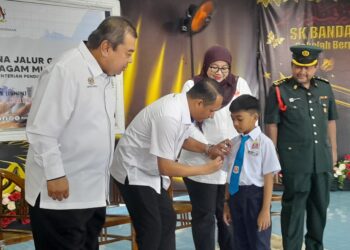 AZNAN Tamin memakaikan lencara Jalur Gemilang kepada seorang murid pada Majlis Peluncuran Lencana Jalur Gemilang di SK Bandar Penawar 2, Kota Tinggi.