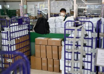 BUNGKUSAN barangan memenuhi ruang hadapan kaunter perkhidmatan di pejabat pos di Hong Kong.-AFP