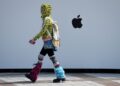 SEORANG wanita berjalan melepasi sebuah kedai Apple di Beijing, China.-AFP