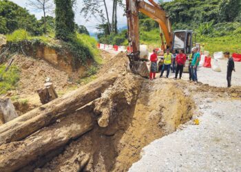 MOHD. Azmawi Fikri Abdul Ghani (kiri) meninjau keadaan jalan sementara yang runtuh sepanjang 30 meter di Kilometer 35, Jalan Gua Musang-Jeli, Kelantan. – UTUSAN/AIMUNI TUAN LAH
