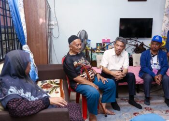 MOHAMAD Hasan menyantuni penduduk pada program Ziarah Kasih PRK Ayer Kuning di Tapah. - UTUSAN/MUHAMAD NAZREEN SYAH MUSTHAFA