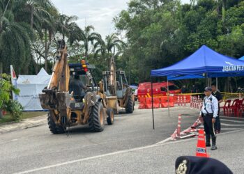 ANTARA kenderaan jenis backhoe yang dibenarkan masuk ke Taman Putra Harmoni, Subang Jaya, Selangor sambil dikawal oleh polis, hari ini.- UTUSAN/AIMAN ALI