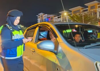 NORAINI Mohd. Nawi memeriksa lesen memandu semasa sekatan jalan raya di Jalan Kampung Bakau-Padang Behor di Kangar, Perlis semalam. UTUSAN/SYED AZLAN SAYID HIZAR