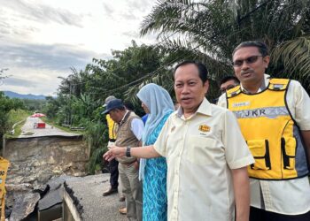 AHMAD Maslan menunjukkan keadaan jambatan Sungai Liat yang runtuh ketika meninjau lokasi kejadian di Felda Sungai Klah di Sungkai hari ini. - UTUSAN/LIYANA RAMLI
