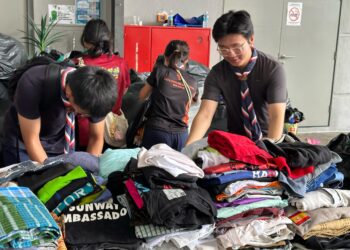 KHOO Ka Min (kanan) melakukan tugas penyusunan barangan dan pakaian bersama kumpulan pengakap di luar PPS Masjid Putra Heights, hari ini. - UTUSAN/AIMAN ALI