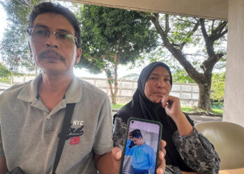 SARIFF Ahmad (kiri) bersama isterinya menunjukkan gambar arwah anak mereka, Mohd. Taufik Ariff Sariff yang maut dirempuh pemandu mabuk di Taman Desa Jaya, Johor Bahru.