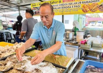 PAK Din menyusun makanan laut yang sedia digoreng bersama tepung mengikut permintaan pelanggannya.