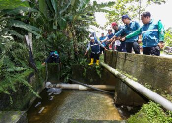 BEBERAPA ahli Jawatankuasa Induk PN pada PRK DUN Ayer Kuning menunjukkan keadaan paip utama dalam longkang yang bocor di sebuah ladang babi di Tapah hari ini. - UTUSAN/MUHAMAD NAZREEN SYAH MUSTHAFA