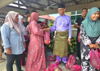 NIK Dir Nik Wan Ku menyampaikan tembikai kepada tetamu yang hadir pada Majlis Rumah Terbuka Aidilfitri UMNO Bahagian Marang di Pulau Kerengga, Marang, Terengganu.  - UTUSAN/ZAID MOHD. NOOR