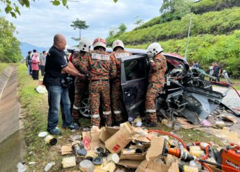 ANGGOTA bomba mengeluarkan mangsa dalam kenderaan yang terlibat kemalangan di Kilometer 4, Jalan Gerik-Kupang, Gerik hari ini. - UTUSAN/IHSAN JBPM