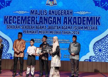 PELAJAR terbaik UPKK negeri, Muhammad Akmal Ariff dari SRA JAIM Tanjung Minyak menerima anugerah kecemerlangan pada Majlis Anugerah Kecemerlangan Akademik Sekolah-sekolah Agama JAIM di Banda Hilir, Melaka. - UTUSAN/AMRAN ALI