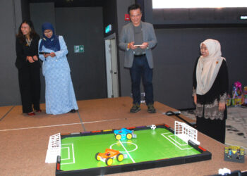 MAHFUDZAH Mohamed Noor mencuba permainan soccer car sebagai simbolik merasmikan Pelancaran Produk Robotik di Bandar Hilir, Melaka. - UTUSAN/AMRAN MULUP