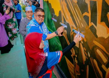 AB. Rauf Yusoh menurunkan tanda tangan di dinding mural SMK Ghafar Baba, Masjid Tanah, Melaka. - UTUSAN/AMRAN MULUP