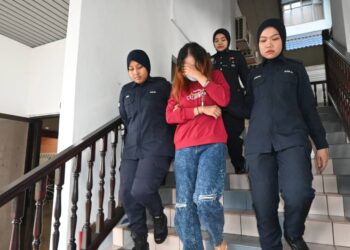 TERTUDUH diiringi anggota polis ketika dihadapkan ke Mahkamah Majistret, Ayer Keroh, Melaka atas pertuduhan menyebabkan janin berusia lima bulan dalam kandungannya mati sebelum dilahirkan. - UTUSAN/MUHAMMAD SHAHIZAM TAZALI