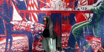 SEORANG wanita berjalan melepasi mural anti-AS berhampiran bekas pejabat kedutaan AS di Teheran.-AFP