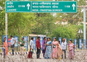 PELAWAT berdiri di sebalik kawat berduri untuk menyaksikan upacara perarakan penurunan bendera berhampiran pos sempadan Wagah antara India dan Pakistan.-AFP