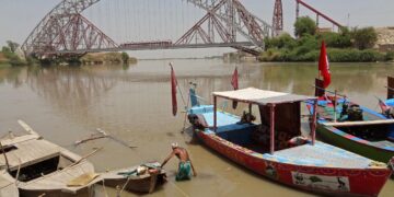 SEORANG lelaki membetulkan botnya di Sungai Indus di Sukkur, wilayah Sind, Pakistan. – AFP