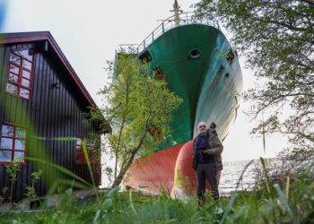 JOHAN Helberg berdiri di hadapan kapal kontena sepanjang 135 meter yang tersadai berhampran laman rumahnya di pesisir Trondheimsfjord di Byneset, Norway.-AFP