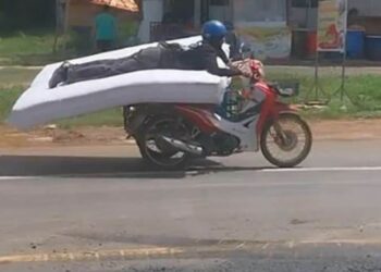 TANGKAP layar video menunjukkan seorang lelaki menunggang motosikal sambil meniarap atas tilam di Thailand. – AGENSI
